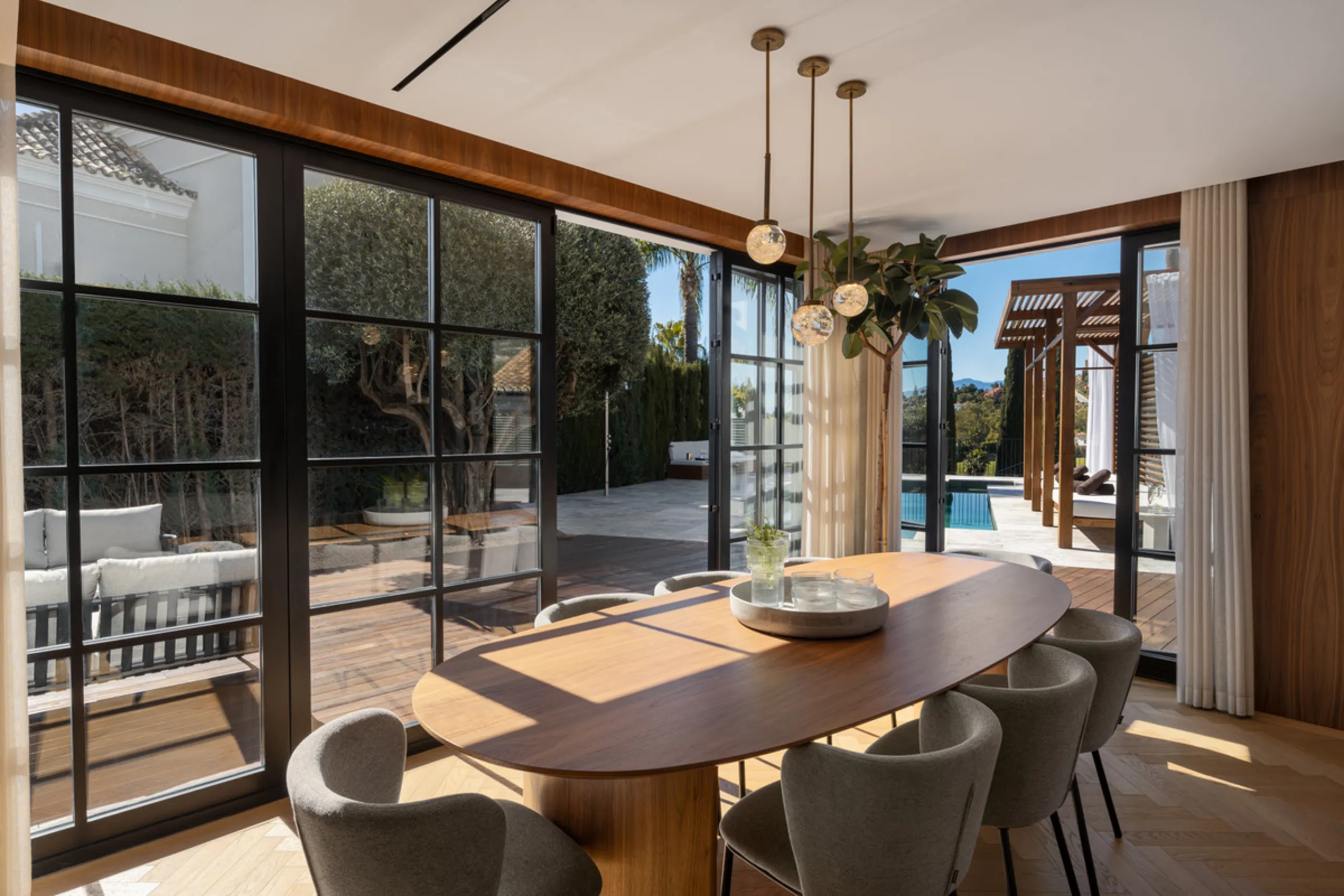 A four-bedroom villa in Nueva Andalucía with open golf and sea views, arranged over multiple levels with a garden-level pool, integrated outdoor kitchen, generous terraces and a private garage.