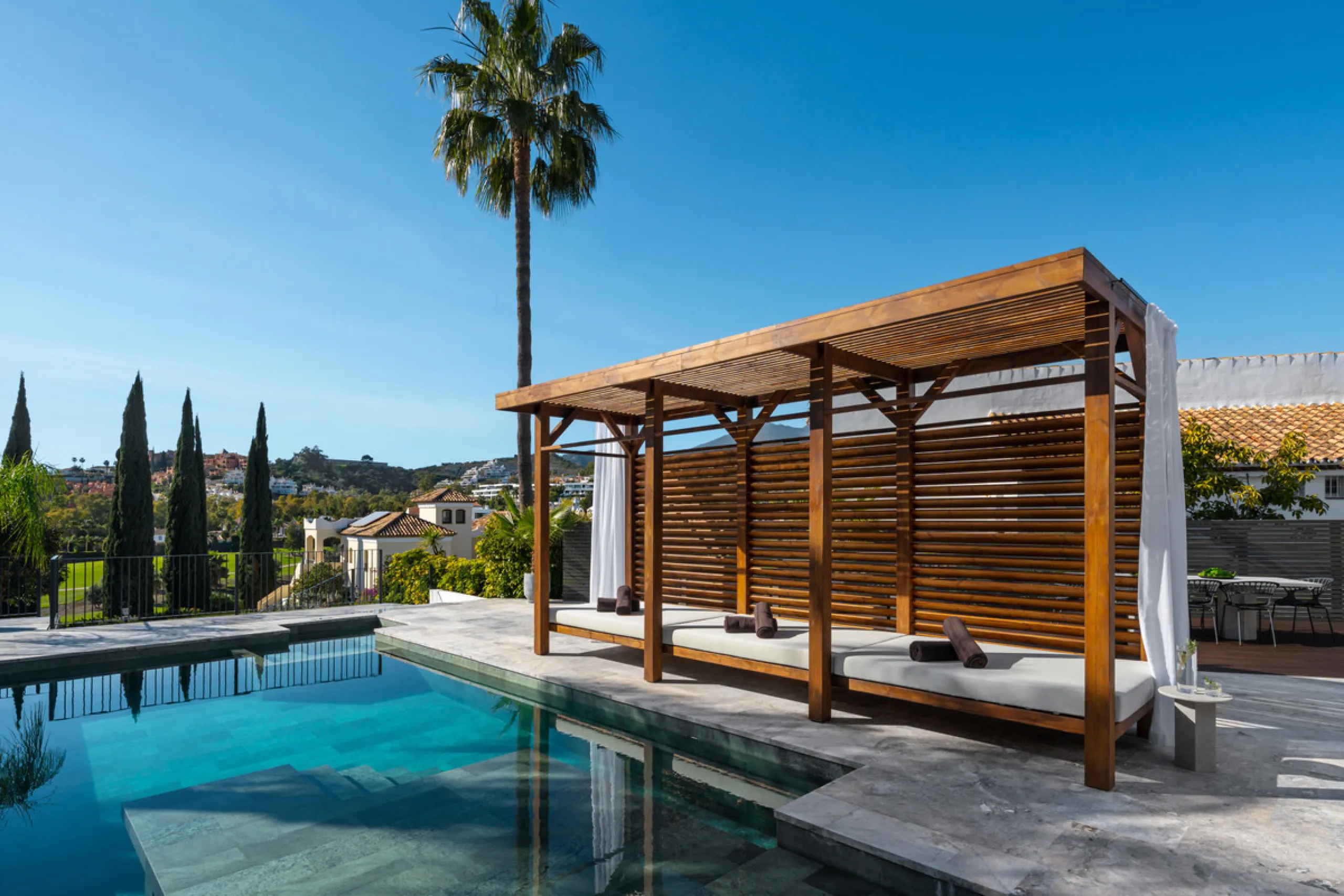 A four-bedroom villa in Nueva Andalucía with open golf and sea views, arranged over multiple levels with a garden-level pool, integrated outdoor kitchen, generous terraces and a private garage.