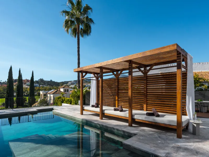 A four-bedroom villa in Nueva Andalucía with open golf and sea views, arranged over multiple levels with a garden-level pool, integrated outdoor kitchen, generous terraces and a private garage.