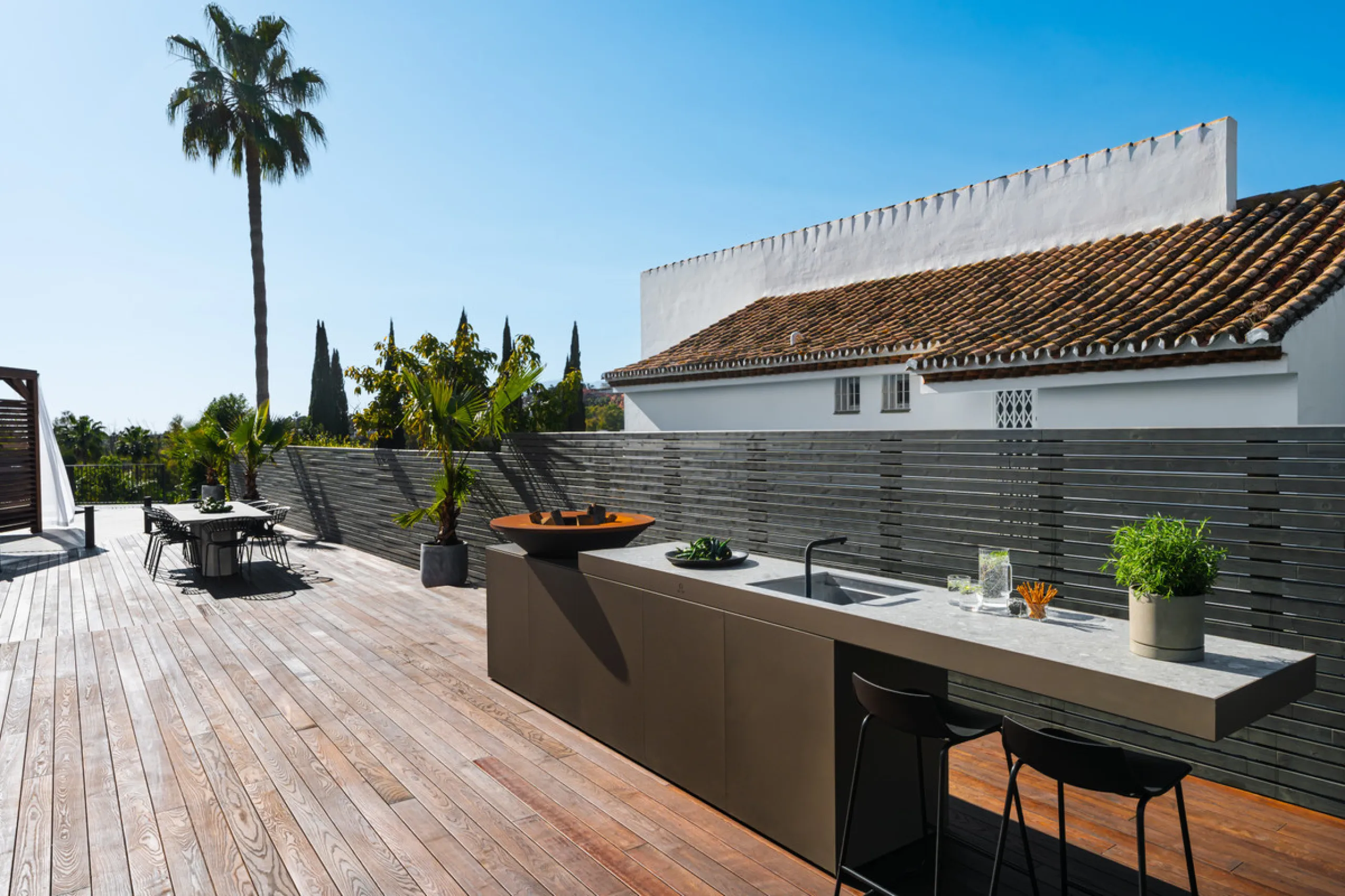 A four-bedroom villa in Nueva Andalucía with open golf and sea views, arranged over multiple levels with a garden-level pool, integrated outdoor kitchen, generous terraces and a private garage.