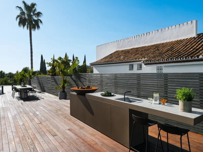 A four-bedroom villa in Nueva Andalucía with open golf and sea views, arranged over multiple levels with a garden-level pool, integrated outdoor kitchen, generous terraces and a private garage.