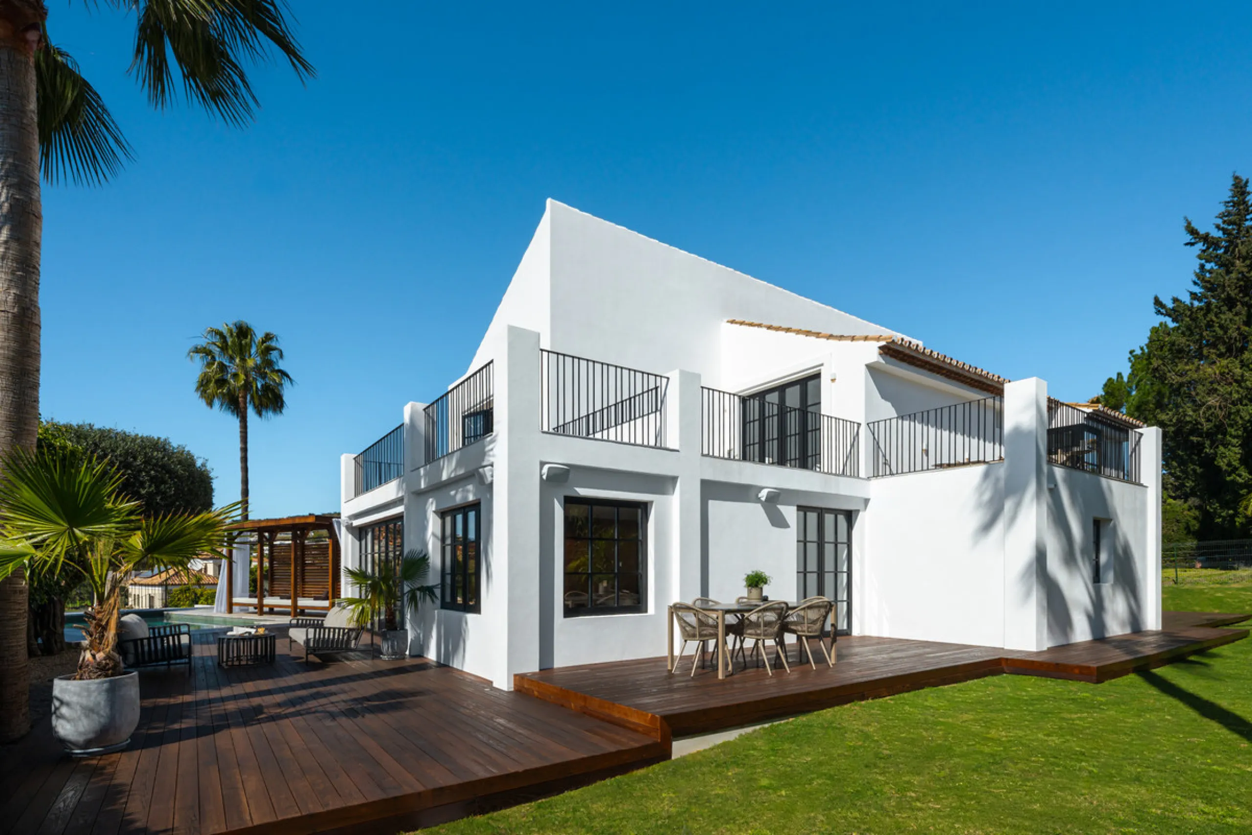 A four-bedroom villa in Nueva Andalucía with open golf and sea views, arranged over multiple levels with a garden-level pool, integrated outdoor kitchen, generous terraces and a private garage.