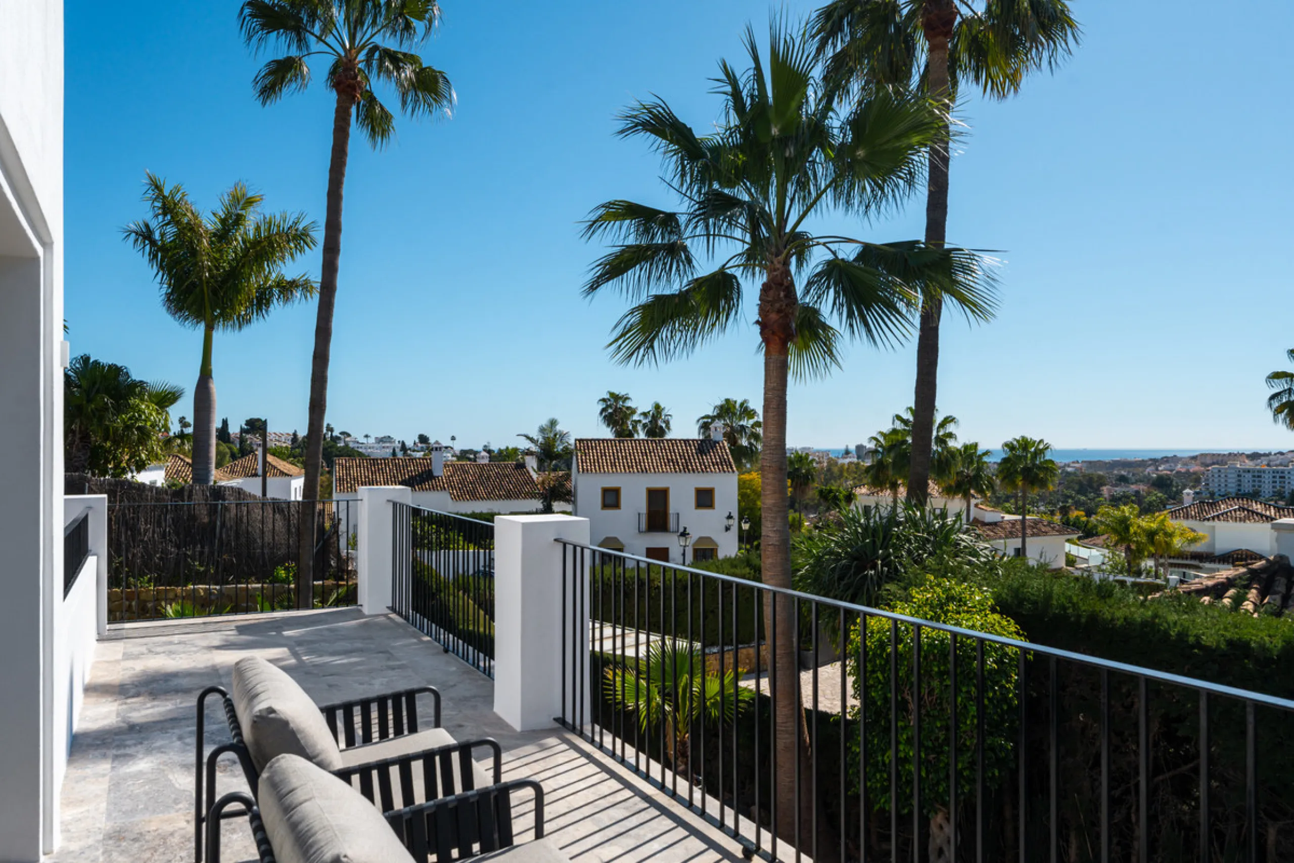 A four-bedroom villa in Nueva Andalucía with open golf and sea views, arranged over multiple levels with a garden-level pool, integrated outdoor kitchen, generous terraces and a private garage.