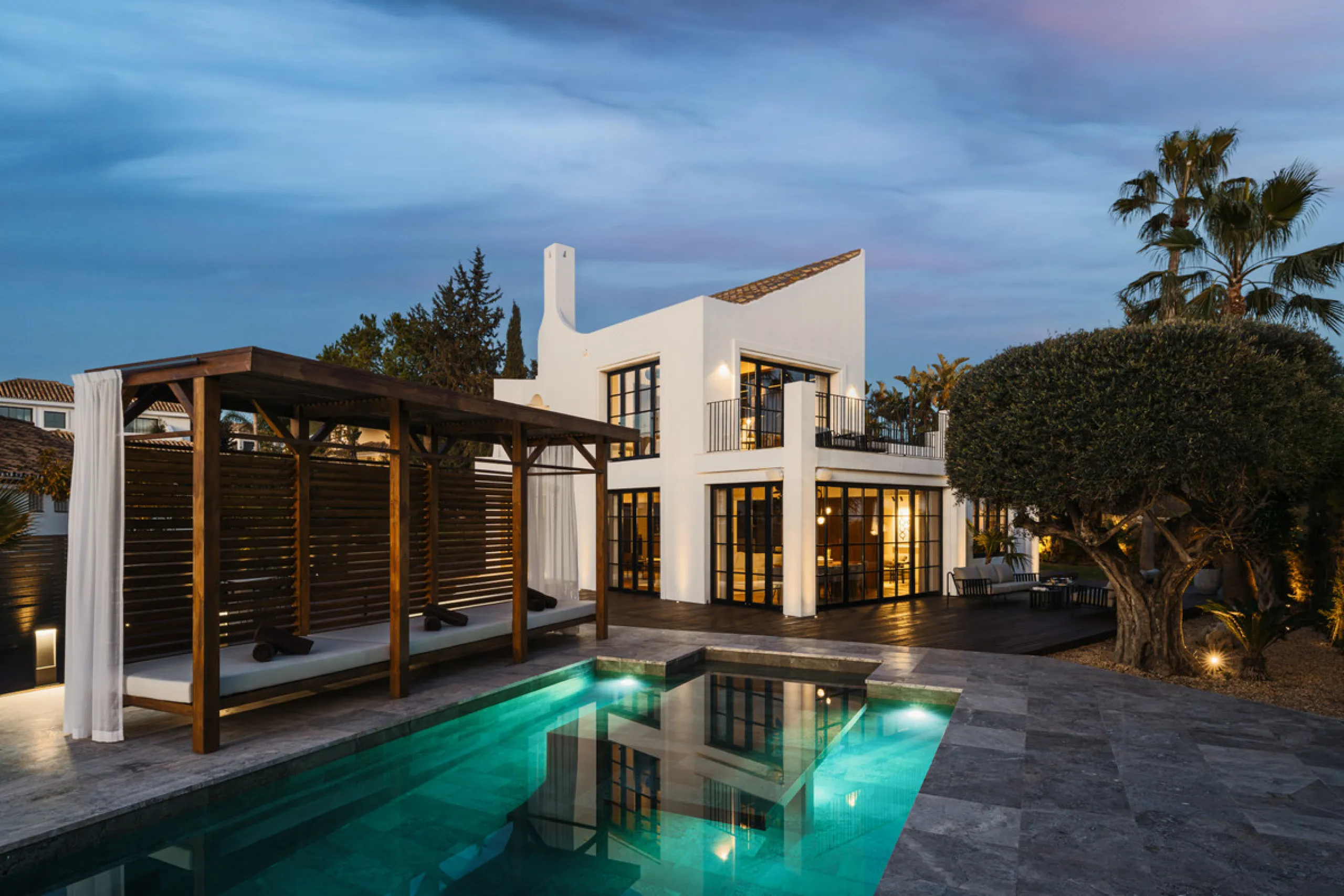 A four-bedroom villa in Nueva Andalucía with open golf and sea views, arranged over multiple levels with a garden-level pool, integrated outdoor kitchen, generous terraces and a private garage.