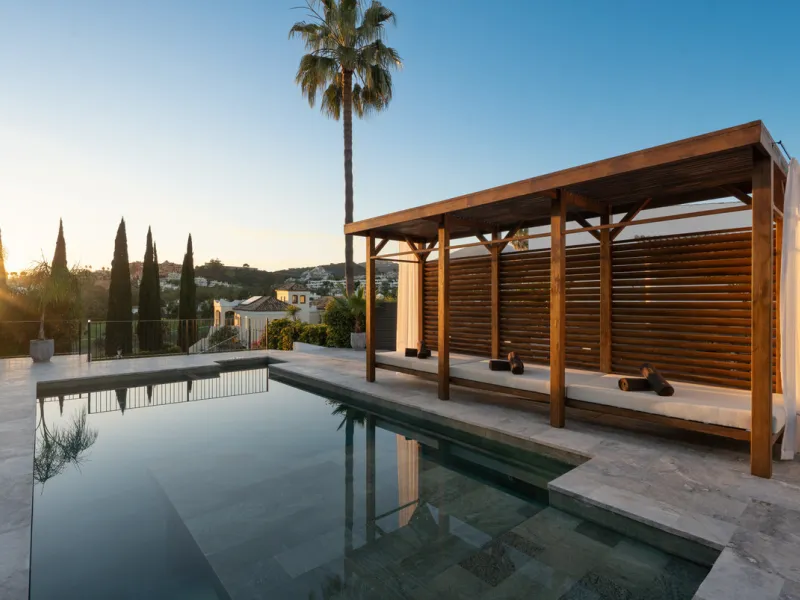 A four-bedroom villa in Nueva Andalucía with open golf and sea views, arranged over multiple levels with a garden-level pool, integrated outdoor kitchen, generous terraces and a private garage.