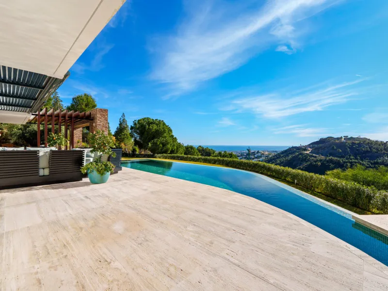 A five-bedroom villa in El Madroñal, Benahavís, offering five bathrooms plus a guest cloakroom, with a first floor dedicated to the master suite with dressing room and library alongside a guest ensuite, a ground floor arranged around formal and informal l