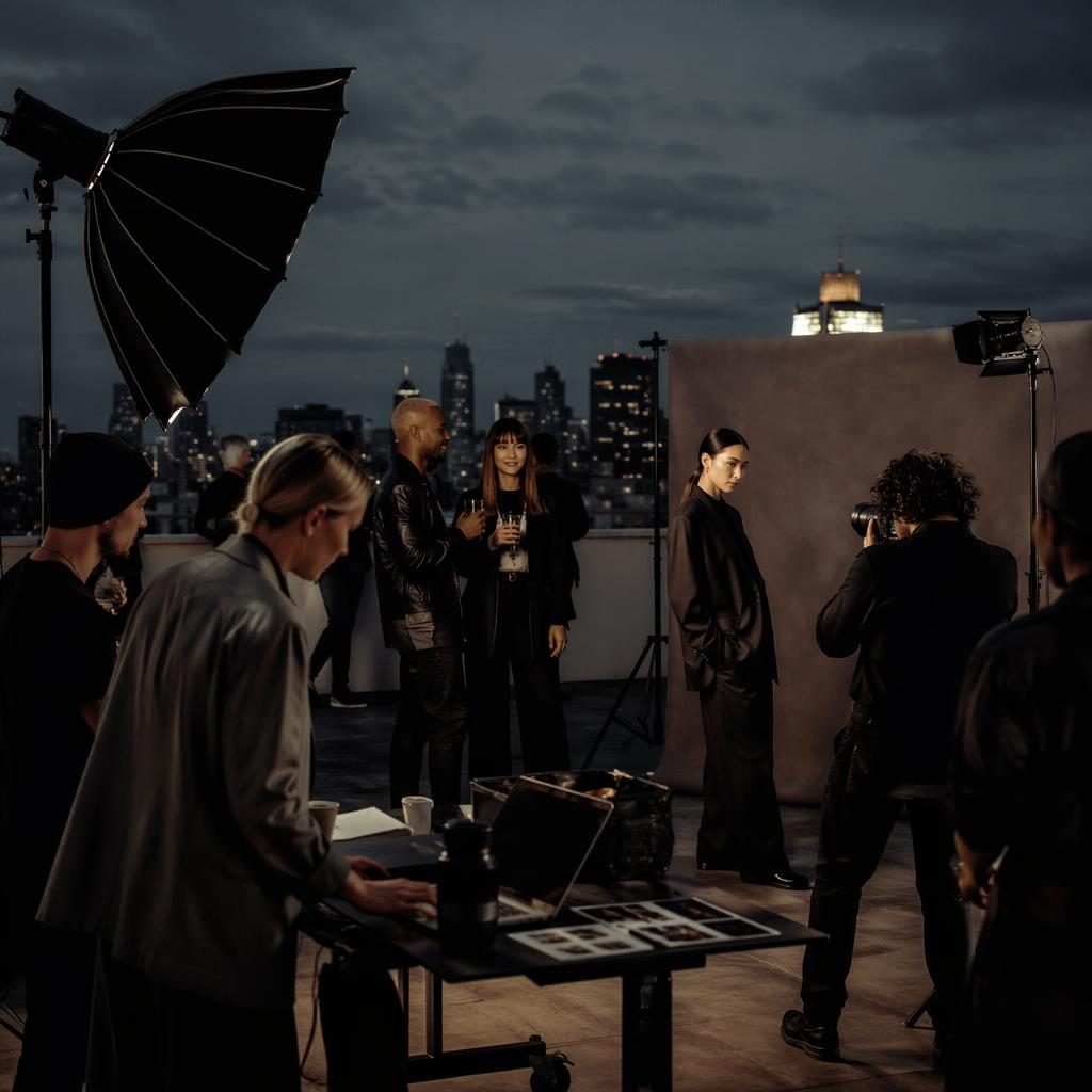Diverses PR-Agentur-Team auf einem Rooftop-Event bei dunkler, editorialer Lichtstimmung ohne sichtbare Logos