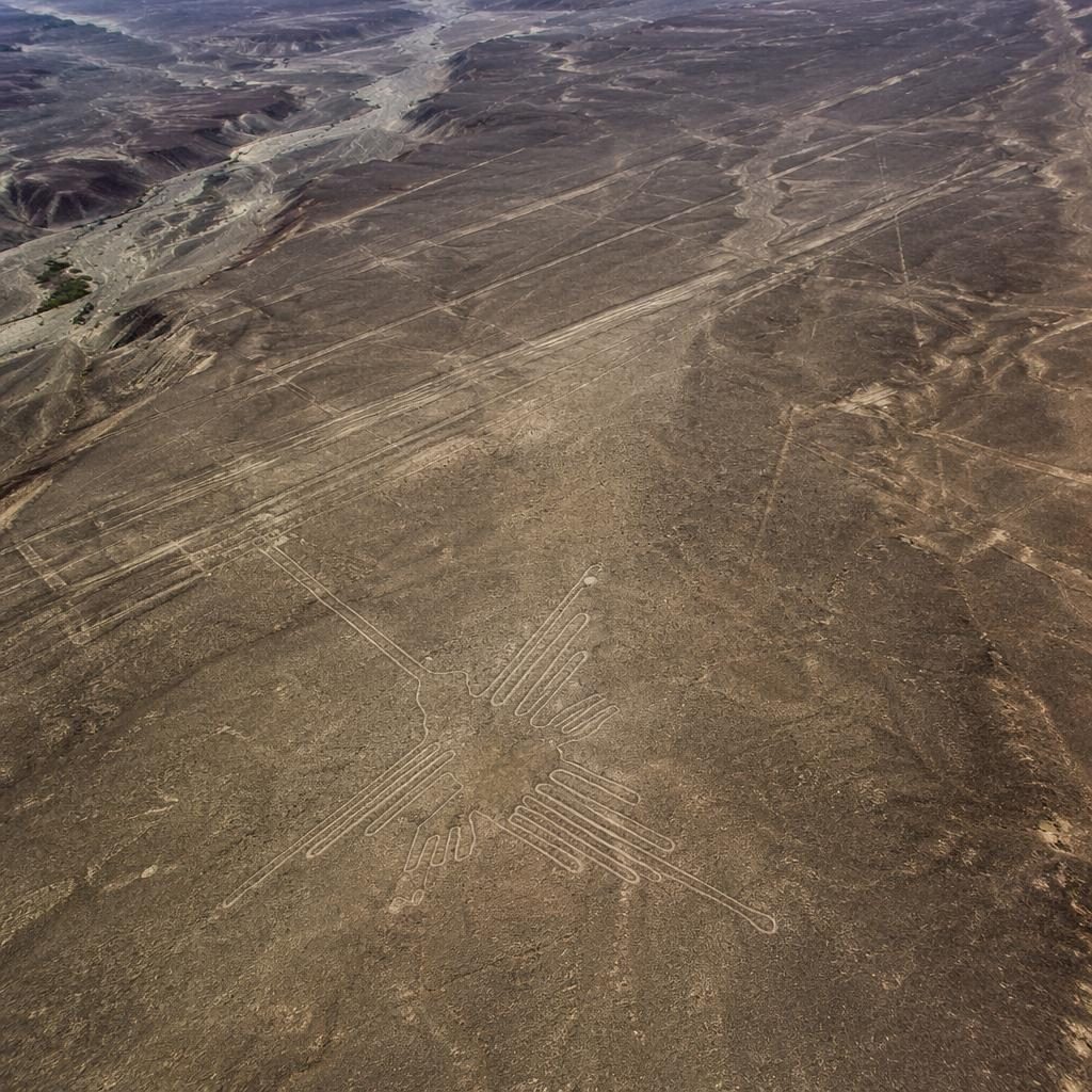 Vista aérea de dron de un río serpenteando por un valle, con detalle cenital nítido, niebla y rascacielos al fondo.