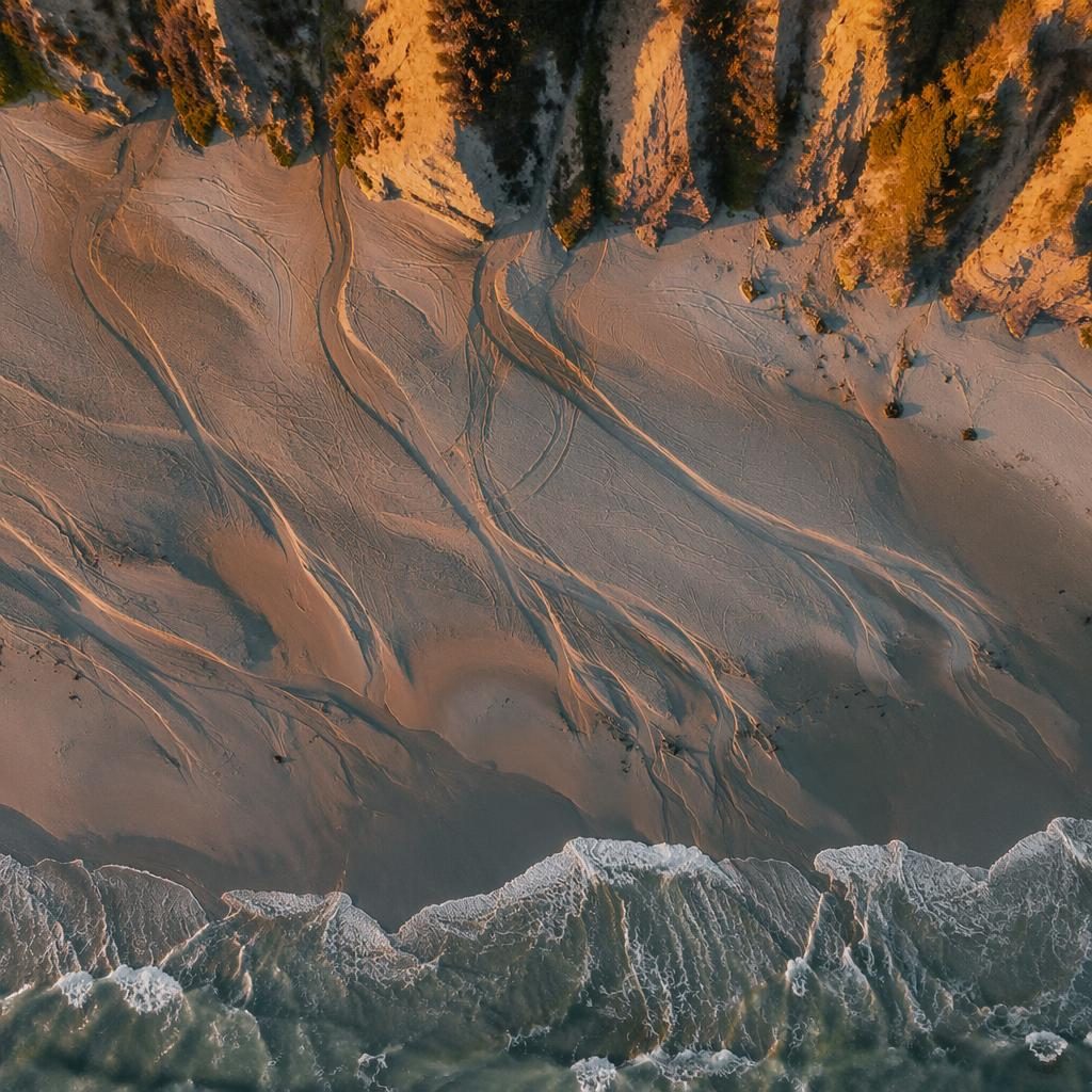 Drone aerial view of rice terraces at dusk with warm sunset light, tilted top-down composition and low-tide tracks.