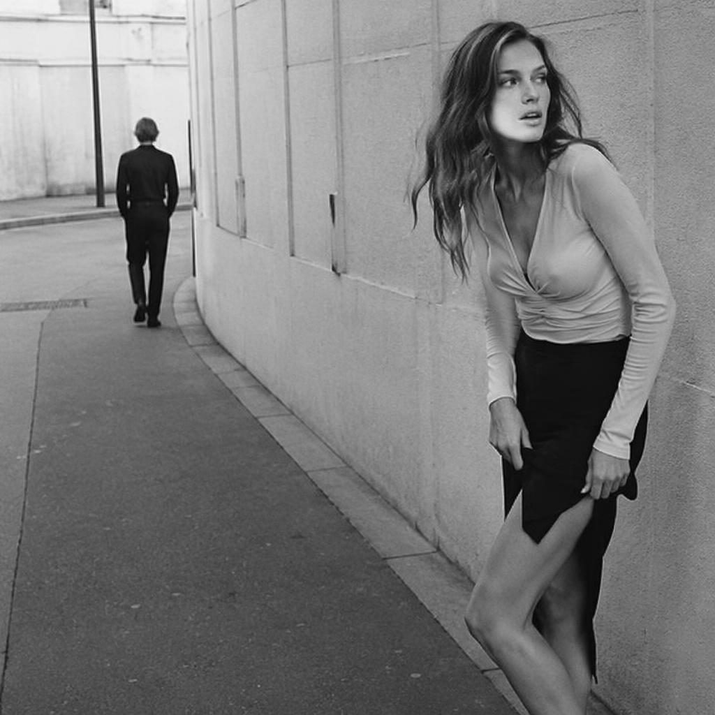 Modèle générique en tenue mode, rue urbaine, ambiance candide et joueuse, palette noir et blanc, style éditorial Y2K.