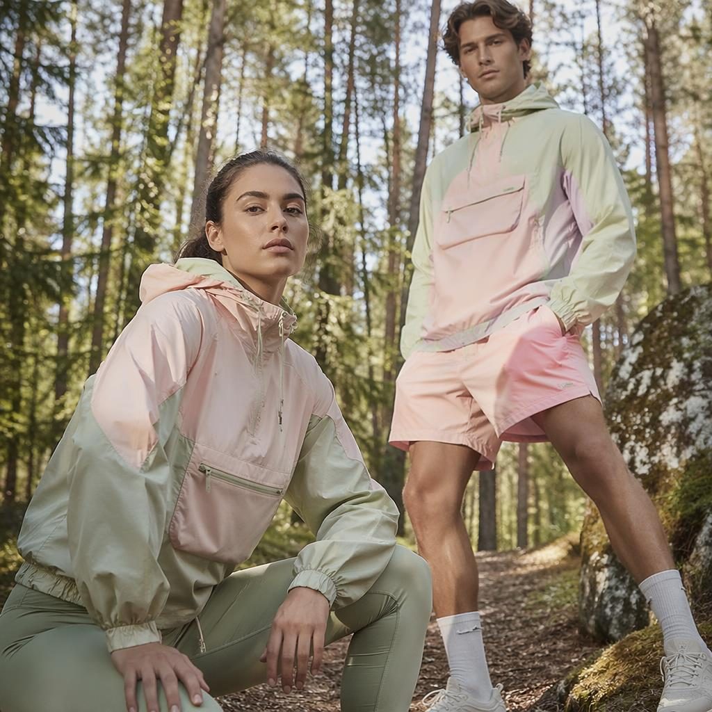 Editorial fashion model in pastel sportswear posing in a forest with bold energy and soft magazine lighting