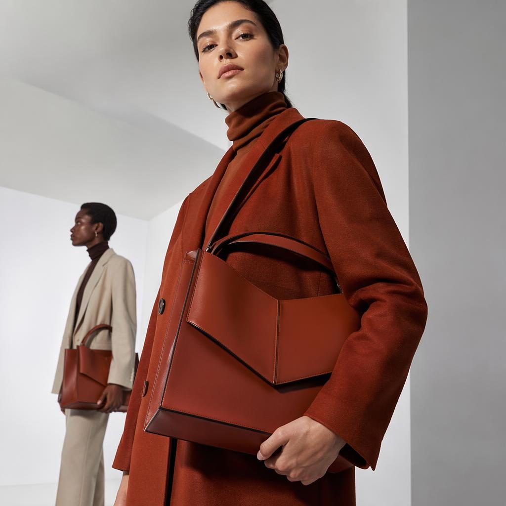 Modelo con taschen moda en look editorial futurista, posando en espacio blanco minimalista con paleta óxido otoñal.