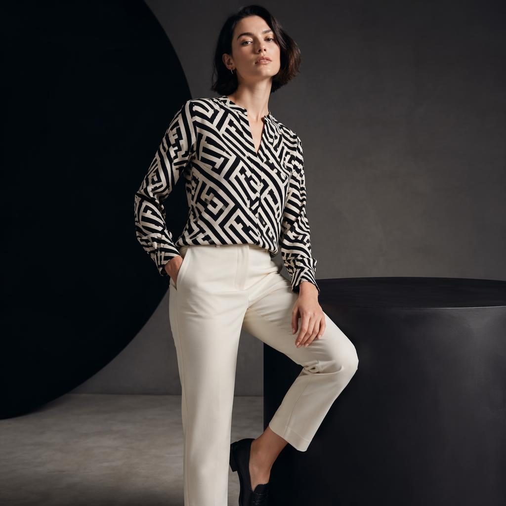 Editorial fashion model in a J McLaughlin catalog outfit posed in a neutral studio with dark moody lighting and bold contrast.