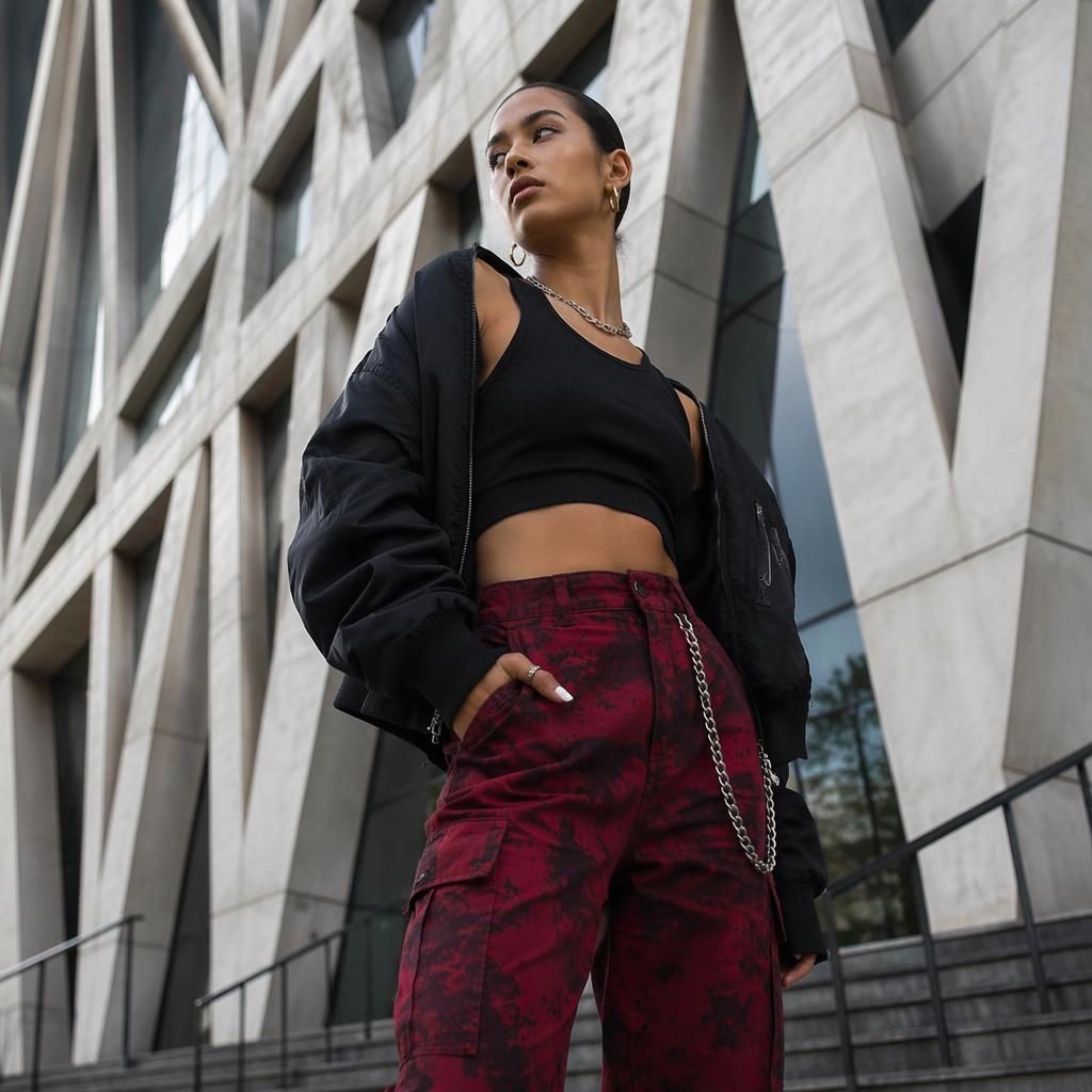Editorial streetwear model posing by a modern architectural building in bold high-contrast lighting