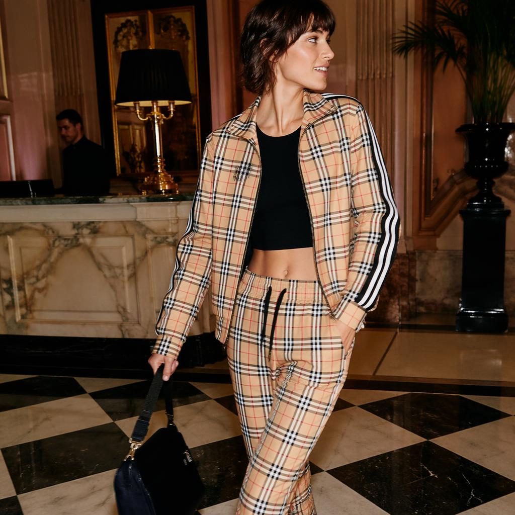 Editorial fashion model in a sporty burberry lookbook outfit posing candidly in a luxury hotel lobby with bold lighting.