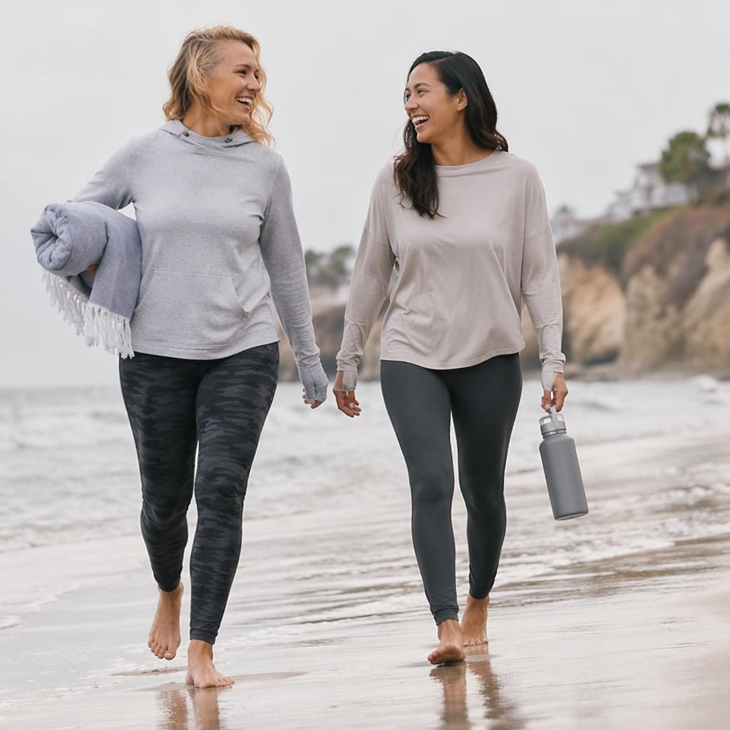 Model in cool gray activewear on a beach in a playful candid pose, styled like an editorial fashion lookbook