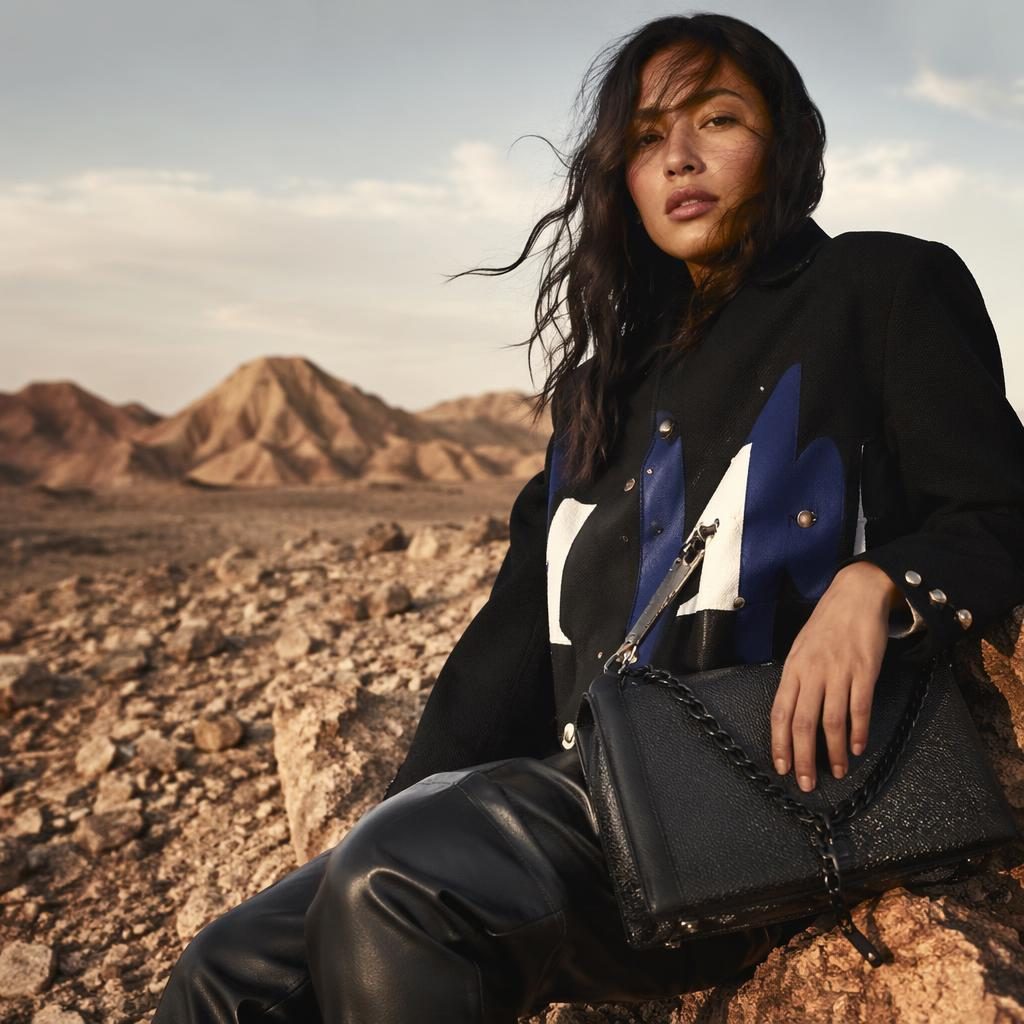 Editorial fashion model in a grunge-inspired SS23 lookbook outfit standing in a quiet desert with warm earth tones