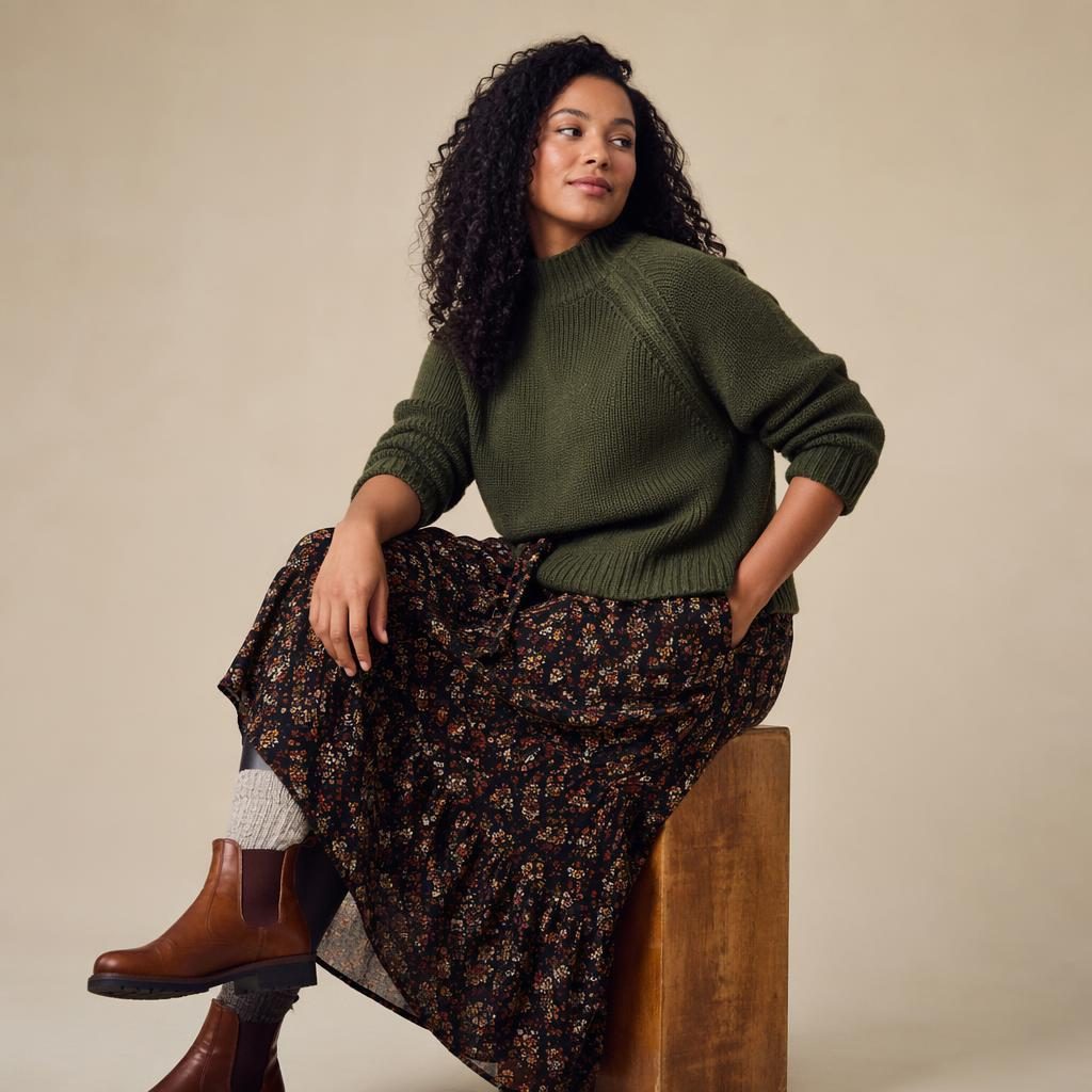 Model in a bohemian flowy outfit poses in a neutral studio with bold high-contrast lighting and a quiet editorial mood.