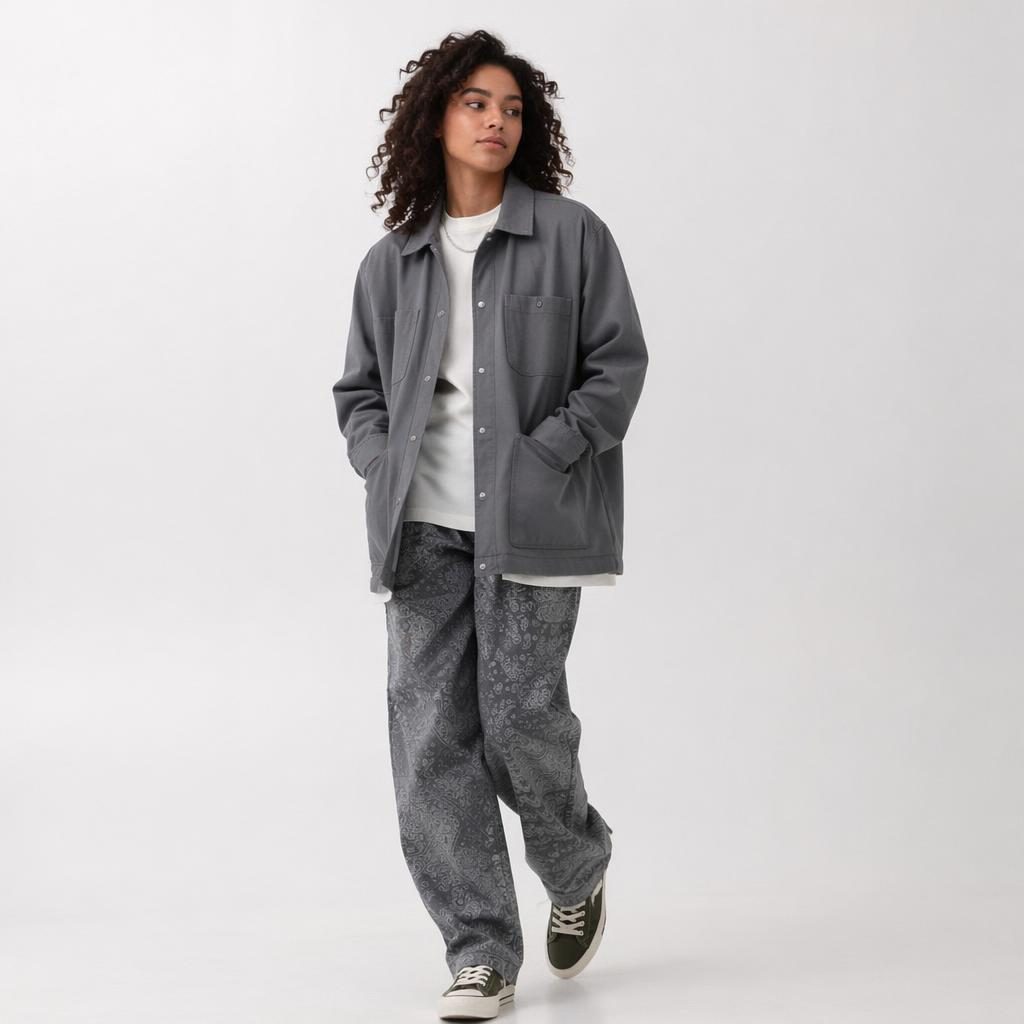 Editorial fashion model in a bohemian flowy outfit posing candidly in a minimalist white studio with cool gray tones.