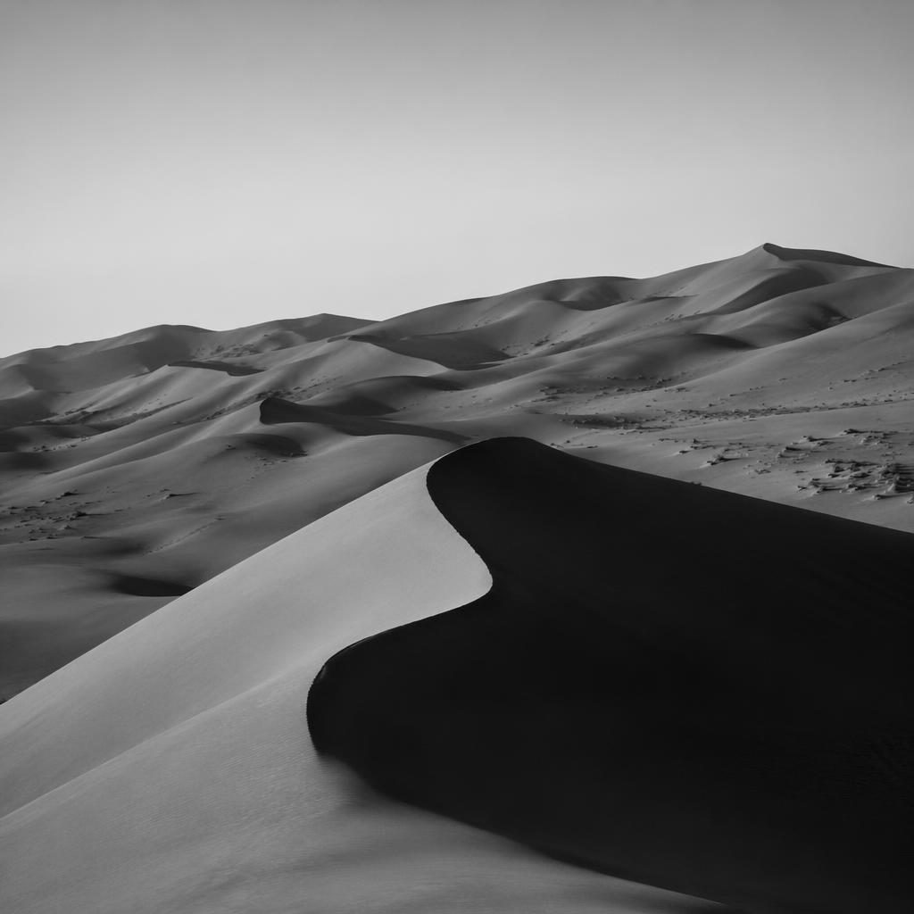 Schwarzweiß-Landschaft mit roten Dünen in Namibia, sanften Hügeln bei blauer Stunde und dramatischem Licht