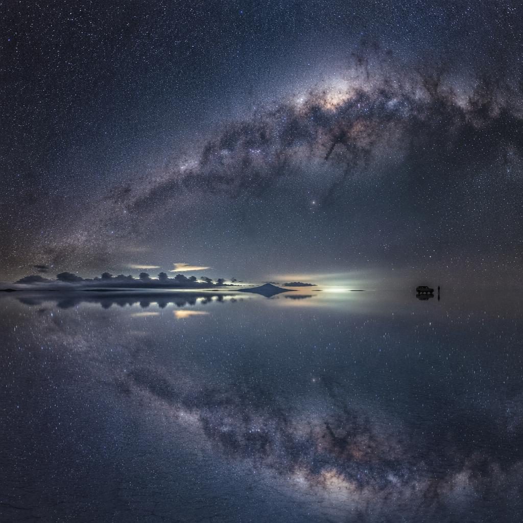 Spiegelnde Salzwüste in Bolivien bei Nacht, mit Milchstraße, dramatischem Himmel und schwarzweißer Naturfotografie.