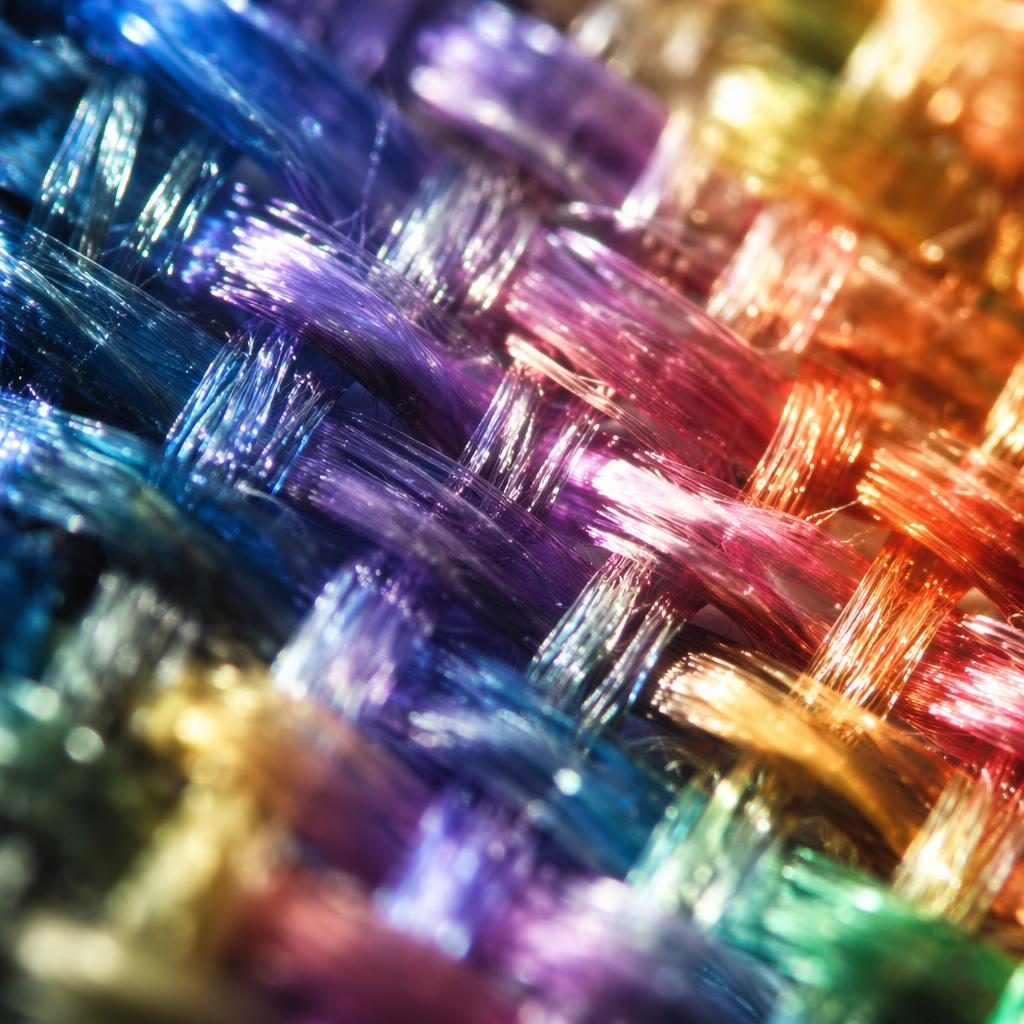 Macro close-up of fabric weave threads with snowflake-like ice crystals, backlit translucence and iridescent rainbow detail.