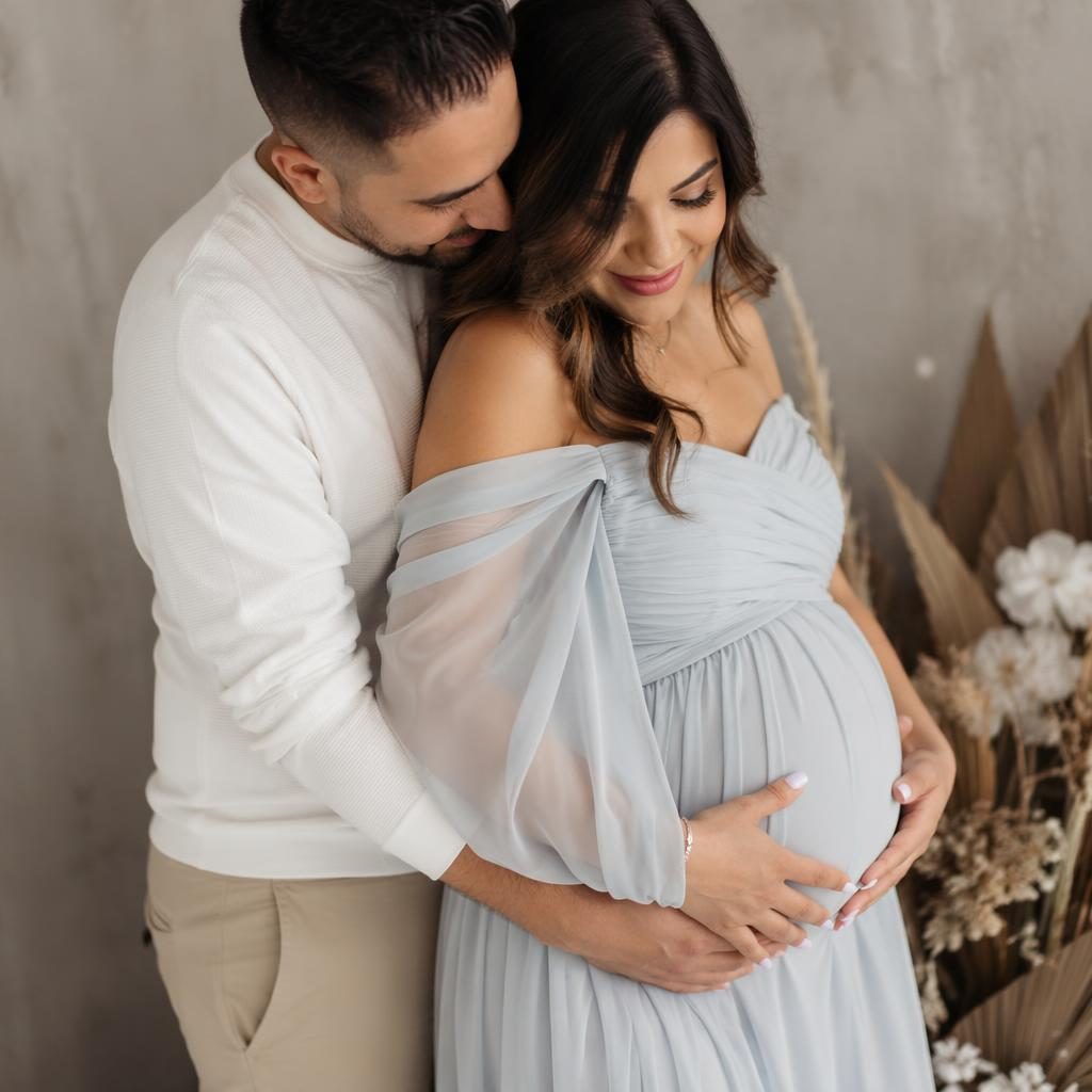 Close-up maternity photo of a pregnant belly with soft autumn leaves, snowy pastel tones, and modern editorial lighting.