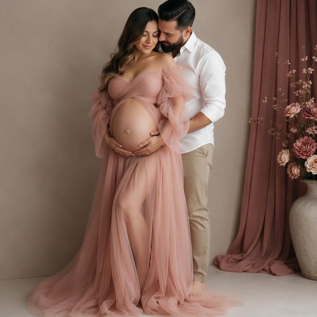 Pregnant mother and partner posing in soft studio light with flowing wardrobe, cream and rose tones, and clean backdrop.