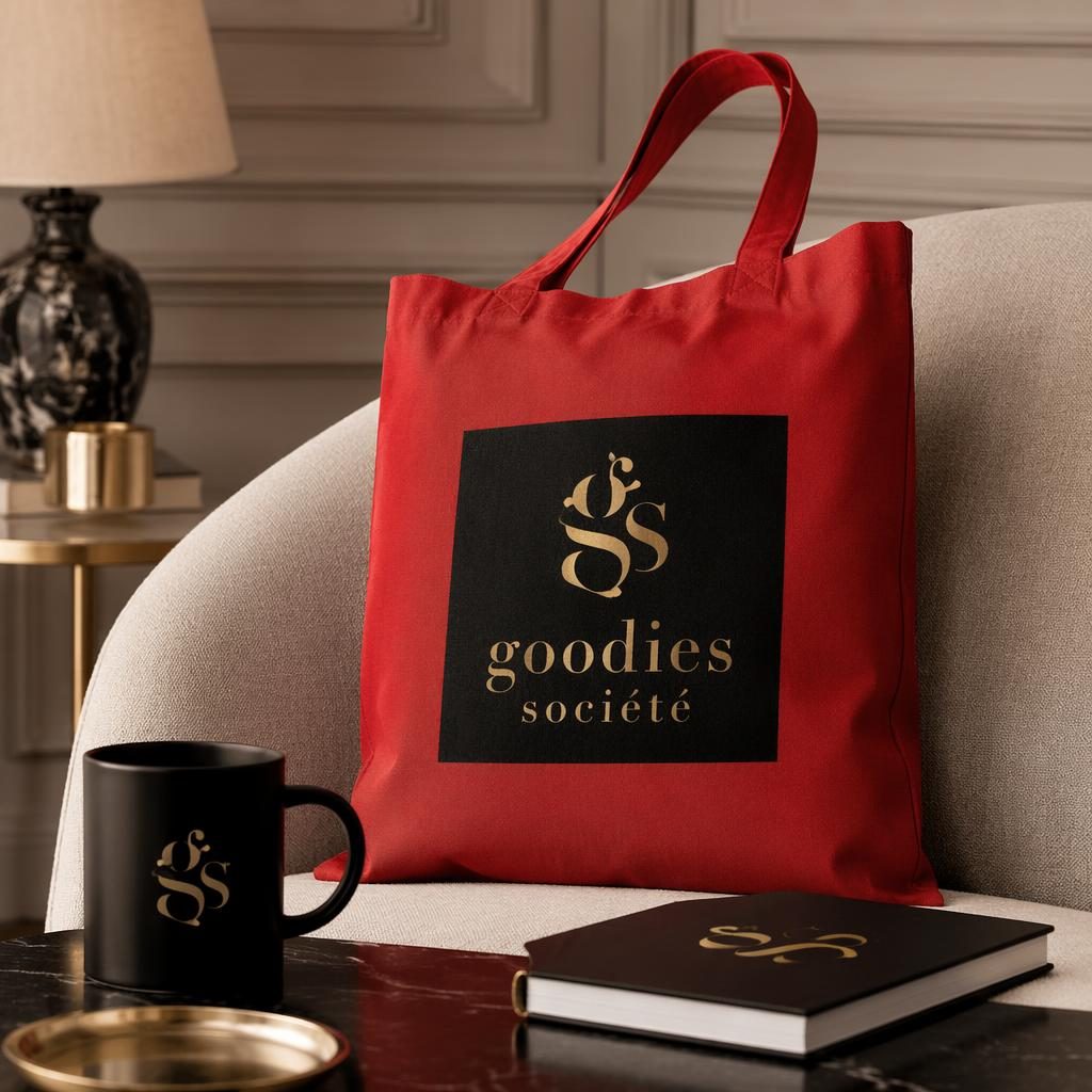 Tote bag rouge avec logo goodies société au dos, style maison cosy, palette noir et or, photo studio nette