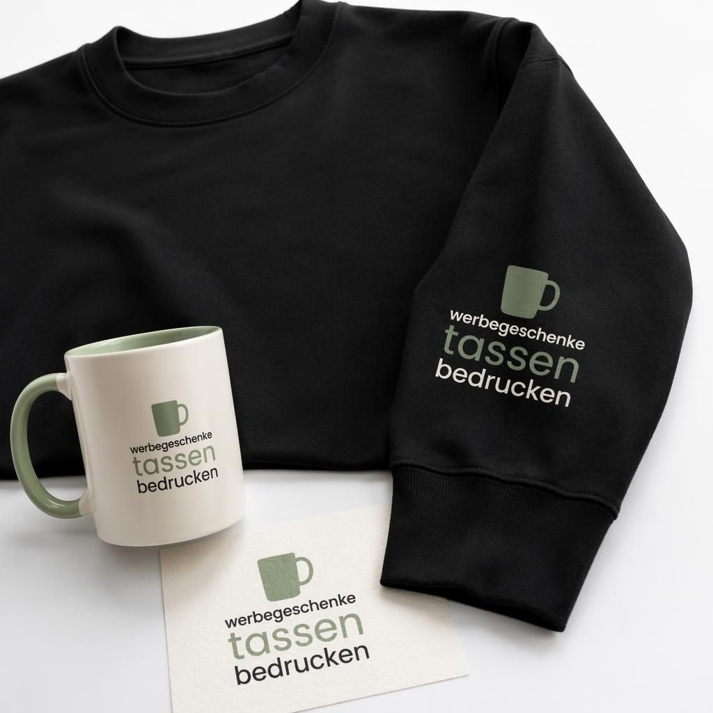 Schwarzes Crewneck auf weißem Hintergrund mit kleinem Logo am Ärmel in Salbei und Elfenbein