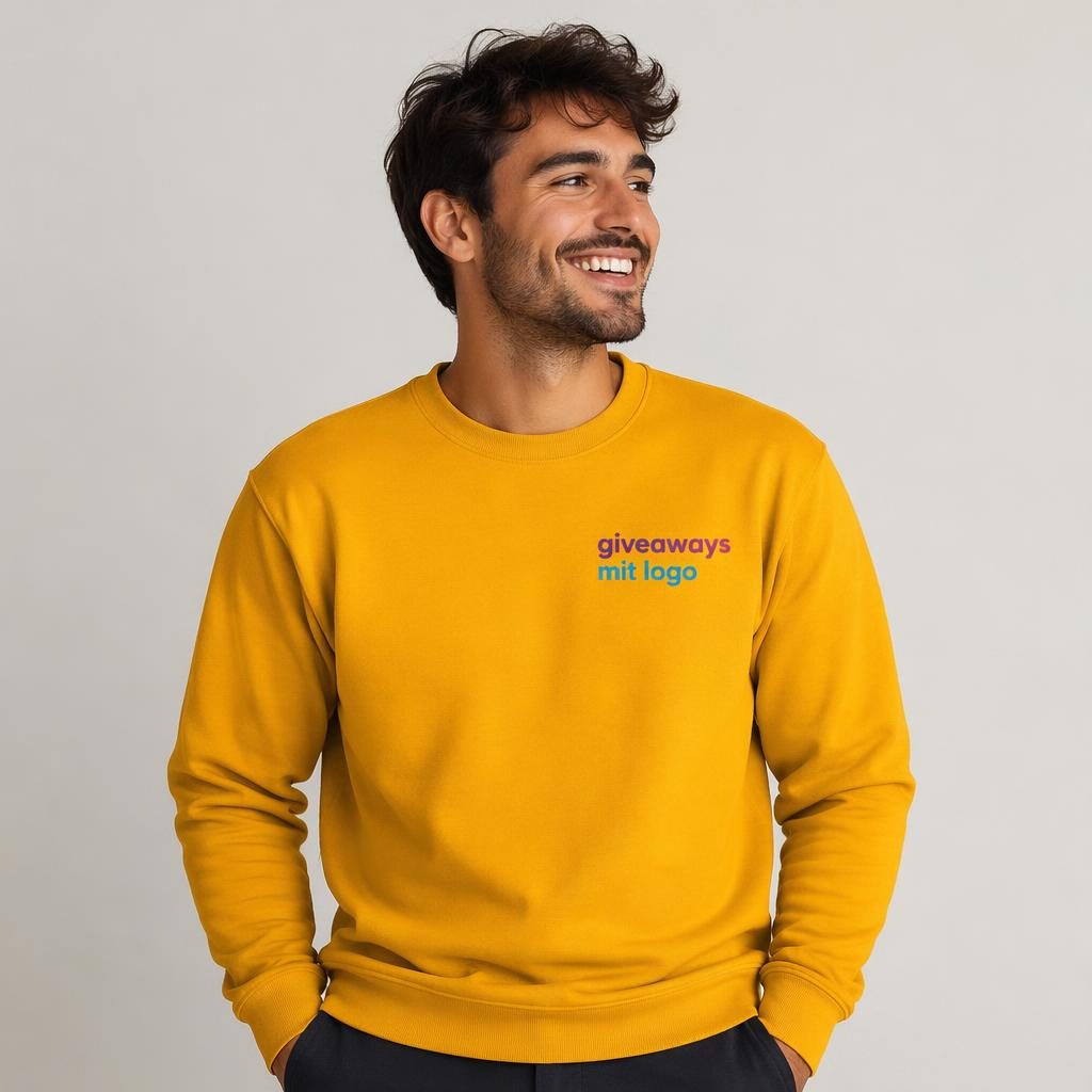 Model trägt senfgelbes Crewneck-Sweatshirt mit kleinem Logo auf der linken Brust vor Studiohintergrund