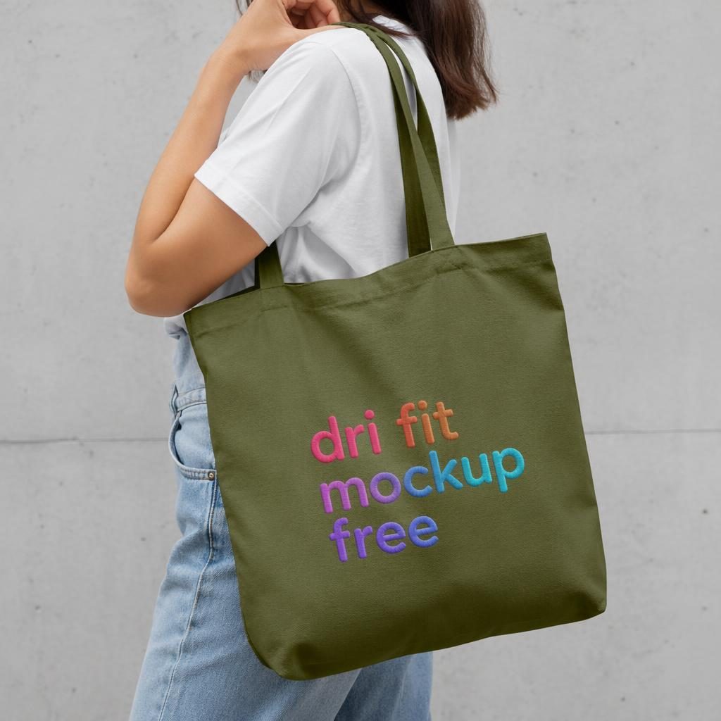 Olive green tote bag worn by a model with a colorful embroidered placeholder logo in a studio product mockup