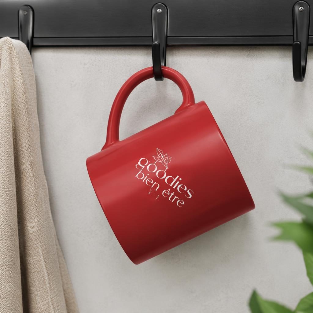 Mug rouge classique suspendu sur un rack, avec logo goodies bien etre au dos, photo studio nette et réaliste.