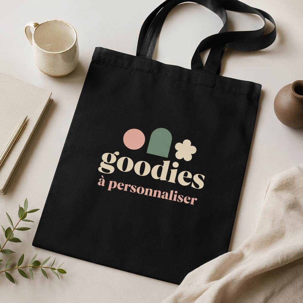 Tote bag noir en flat lay studio avec logo pastel goodies à personnaliser, texture textile nette et rendu réaliste