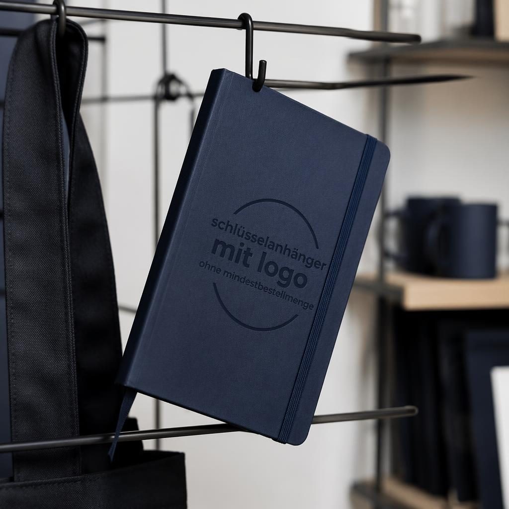 Fotorealistisches navyfarbenes Notizbuch mit dezentem Ton-in-Ton-Logo, hängend an einem Rack im Studio