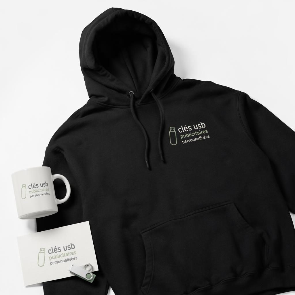 Mockup photo réaliste d’un hoodie noir sur fond blanc, avec logo brodé en tons sauge et ivoire.