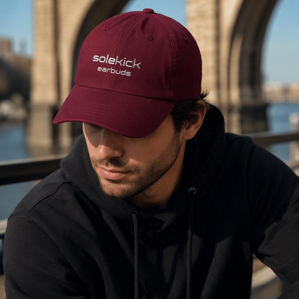 Photoreal burgundy cap mockup with solekick earbuds logo, outdoor lifestyle styling, sharp fabric texture