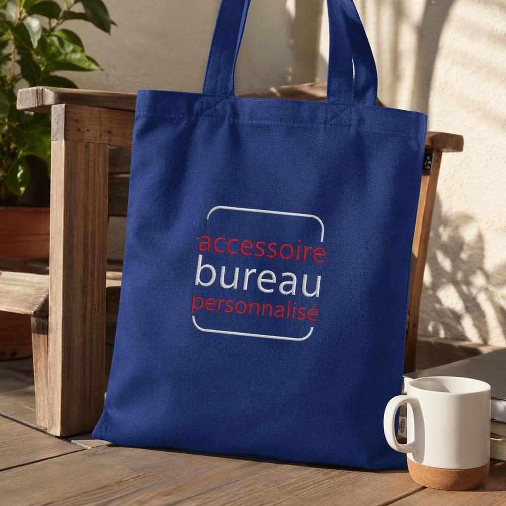 Tote bag bleu royal en tissu avec logo rouge et blanc brodé, photographié en extérieur, rendu net et réaliste.