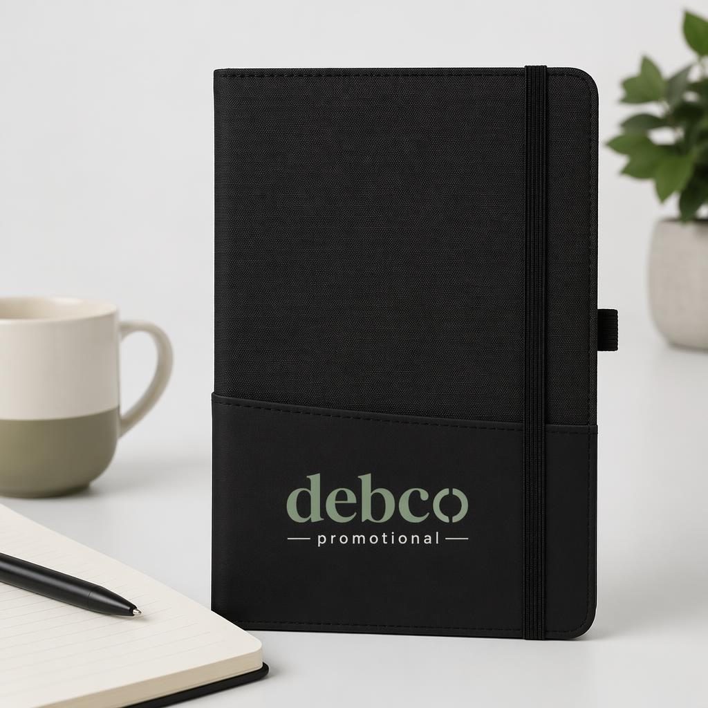 Black notebook product mockup with debco promotional logo on sleeve, set on a minimalist white studio background.
