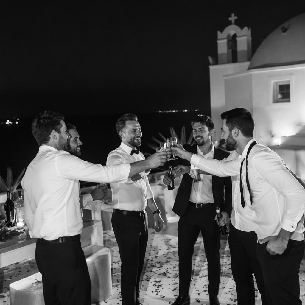 Pareja intercambiando votos en una ceremonia de boda invernal, en blanco y negro, en un recinto blanco estilo isla griega.