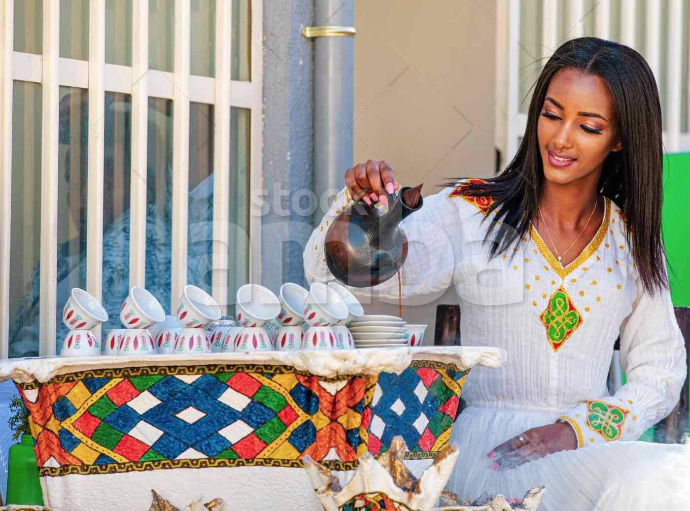 A Woman with Ethiopian Cultural Dress Pouring Coffee StockAMBA