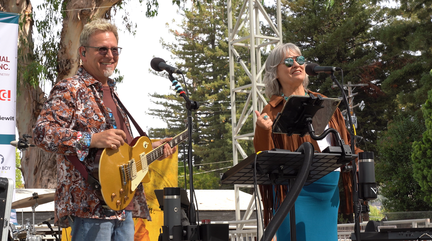 Robert Cassard and Bara Waters of Cosmic Spin sharing a lighthearted moment with the audience during a live performance at the Napa Valley Expo